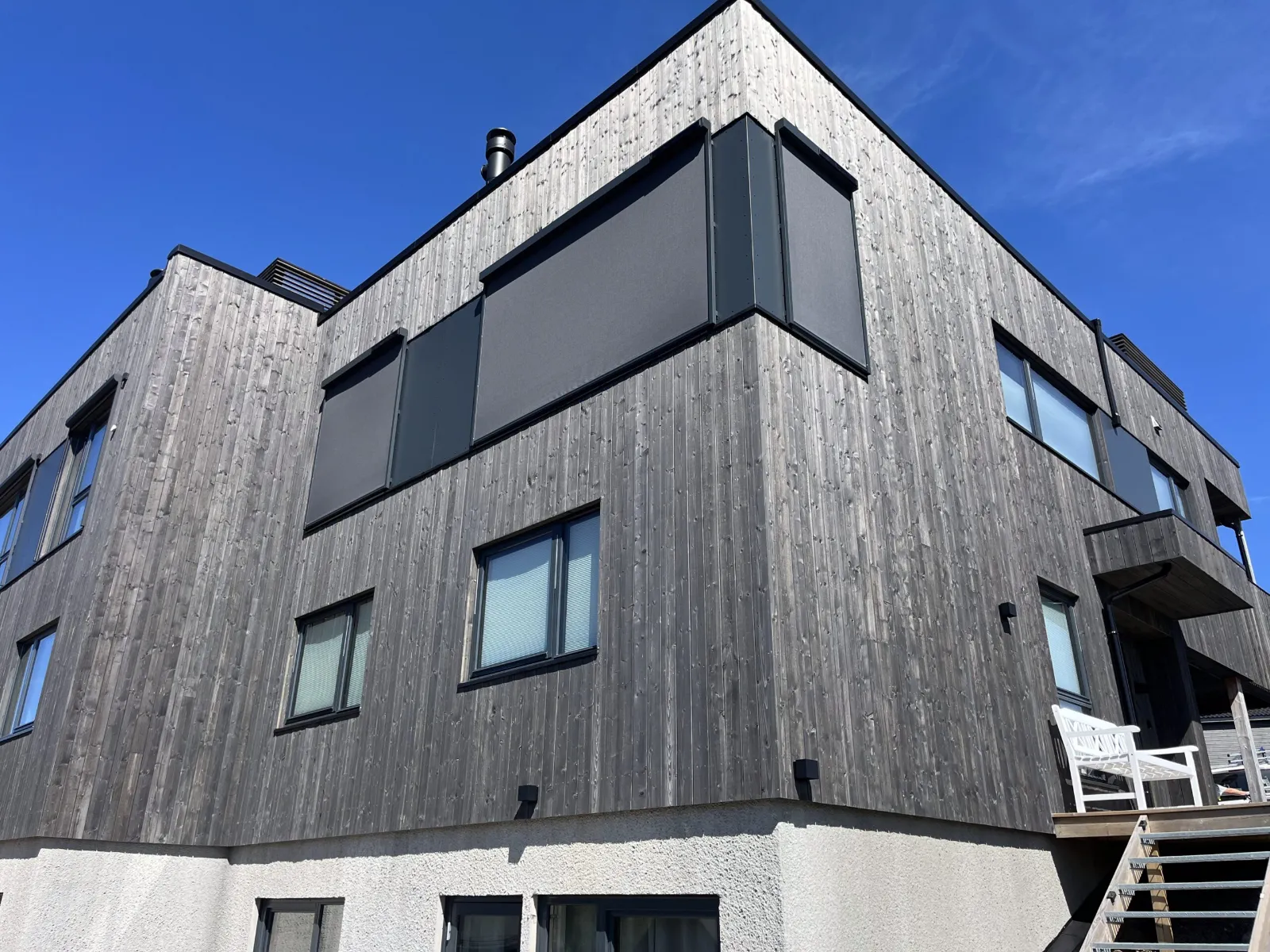 Enebolig med mørk trekledning og utvendige screens på vinduene